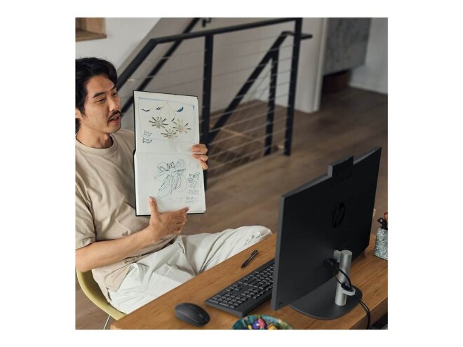 Copy electronic vam predstavlja Stolno račnalo HP 24-cr0048ny R5 All in One 23.8" 16GB, SSD512GB, Free dos [9R7Z0EA#BED]. Na fotografiji je ured, u kojem je je radni stol a za njim sjedi covjek. On u ruci drži blok sa nacrtanim slikama a ispred njega na stolu je računalo