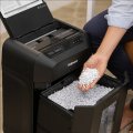 Coyp electronic vam predstavlja Uništavač papira Fellowes AutoMax™ 80M, razina sigurnosti P-4, do 100 listova A4, rez 4x12 mm, kapacitet spremnika 17 l. Na fotografiji je uređj u uredu a pokraj njega je žneksa osoba koja sjedi i jednom rukom stavlja papir u uništavač.