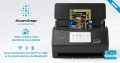 Copy electronic vam predstavlja Skener Ricoh Fujitsu ScanSnap iX2500, A4, duplex, 45 str./min / 90 ipm, Wi-Fi, Bluetooth, crni. Ksener se nalazi na bijlom stolu. Sa gornje ulazne strane se nalazi papir spreman za skeniranje. Sa lijeve strane je laptop a sa desne strane je stalak za olovke i stolni sat.