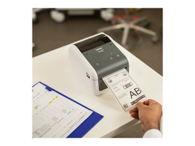 Copy electronic vam predstavlja Printer za neljepnice BROTHER Label TD4410D. Na fotografiji je printer koji je na stolu. Na printeru je primjer isprintane naljepnice i ljudska ruka koja drži tu naljepnicu